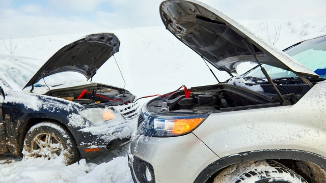 two cars in the snow with jumper cables