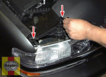 Twist the headlight housing mounting rod(s) (arrows) out of their clips and pull them straight up to disengage the housings