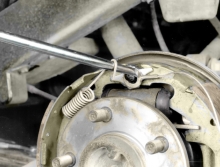 Install the hooked end that’s farther away from the coiled part of the front return spring to the anchor pin with a brake spring