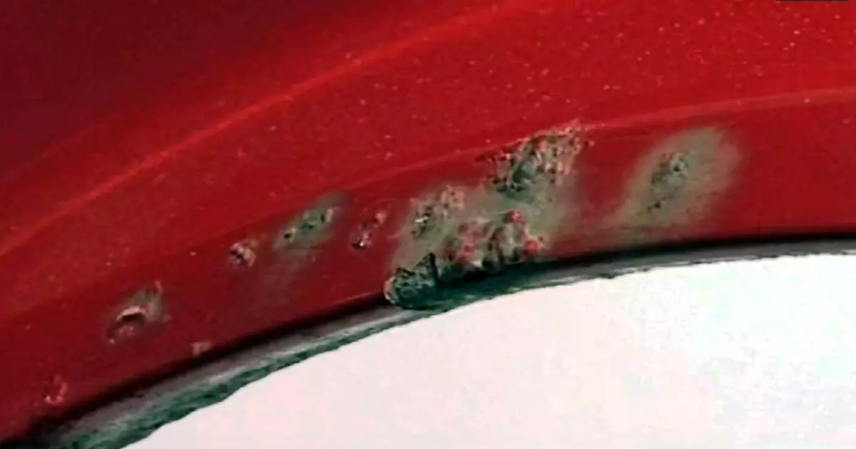 Closeup of side part of auto wheel and fender with cracks, dents
