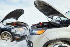 two cars in the snow with jumper cables